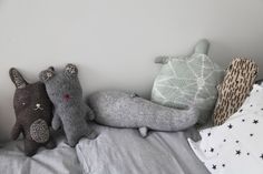 three stuffed animals sitting on top of a bed next to pillows and pillowcases