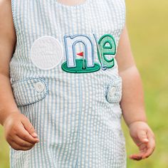 a small child wearing a blue and white striped romper with the letter n on it