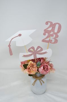 a bouquet of flowers in a mason jar with the number 20 and graduation hat on top