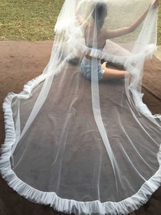 a woman sitting on top of a bed covered in a white veil