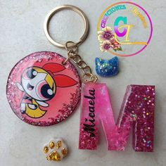 a pink keychain with the letter m on it next to some other items