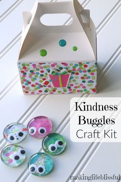 a paper bag with some eyes on it next to buttons and a box that says kindness buggies craft kit