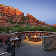 an outdoor dining area with tables and chairs near the mountains at dusk, surrounded by red rock formations