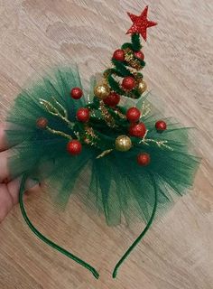 a hand is holding a green tulle christmas tree headband