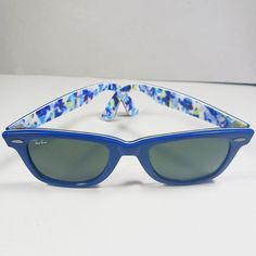 A vintage pair of blue/white Special Series floral motif RB2140 Wayfarer handmade unisex sunglasses from Ray Ban. . Brand: Ray Ban. . Model: RB2140 1019 50 22. . Series: Original Wayfarer Rare Prints. . Color: Blue, blue green and white floral patterns on the interior. . Lenses: Green, 100% UV Protection, G-15 Lens. . Hand made in Italy. Pre-owned, good condition. Few scratches on the original lenses and frame. Structurally and mechanically sturdy and sound. Please see photos. It comes in an aft Retro Blue Polarized Sunglasses, Retro Blue Sunglasses With Polarized Lenses, Retro Blue Sunglasses For Spring, Retro Blue Wayfarer Sunglasses, Vintage Blue Sunglasses For Summer, Blue Vintage Sunglasses For Summer, Handmade Sunglasses, Unisex Sunglasses, Eyewear Sunglasses