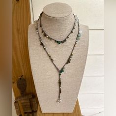 a necklace is displayed on a mannequin with other jewelry items in the background