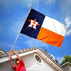 a man holding the texas state flag on top of a house