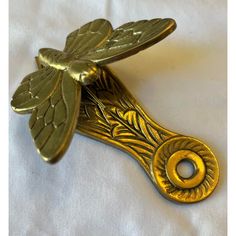 a golden dragonfly brooch pin on a white sheet with gold trimmings