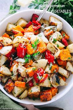 a white bowl filled with roasted vegetables on top of a green cloth next to a fork