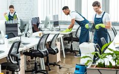 two men in aprons cleaning an office cubicle with plants on the desks