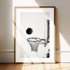 a black and white photo of a basketball going through the hoop