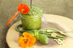 a green smoothie in a jar with flowers on the side