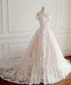 a wedding dress is displayed on a mannequin in front of a white wall