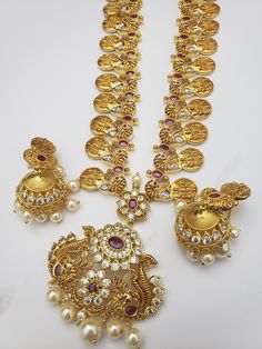 "Handmade Indian Jewelry, best to wear for traditional ceremonies or Indian wedding. This bridal jewelry has an ethnic finish. It has Cubic Zircon stones with semi-precious rubies. It is a Bollywood style one gram jewelry. Handmade Indian Jewelry item * Necklace Set is a combo of Necklace & jumka Earrings * Necklace is adjustable with adjustable back chain/ Dori/ Cord * Earring Length: 2\" , Earring Width: 1.25\" * Necklace length; 32\" approx * Gold Color is a gold-tone which has a beautifu Temple Jewelry Necklaces With Stone Setting, Traditional Round Necklaces With Stone Setting, Gold Kundan Necklace With Stones In Temple Jewelry Style, Traditional Round Kundan Necklace With Stones, Traditional Yellow Gold Jewelry With Stones, Heavy Temple Style Long Necklace, Kundan Long Necklace Temple Jewelry, Festive Gold Temple Necklace With Stones, Festive Hand Set Round Temple Necklace