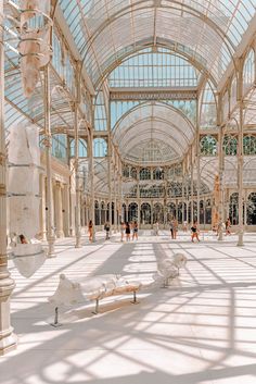 the inside of a building with people walking around and some statues on the ground in front of it