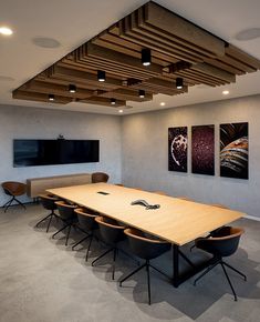 a conference room with wooden tables and chairs in front of a flat screen tv mounted on the wall