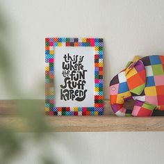 a colorful elephant sitting on top of a wooden shelf next to a framed print with the words, this is where we don't stuff shaped