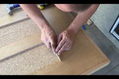 a man sanding wood on the floor with a pair of hands holding a piece of wood