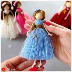 a hand holding a small doll with four other dolls behind it