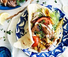 a taco filled with meat and vegetables sitting on top of a blue and white plate