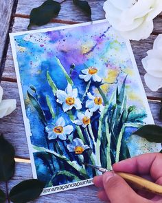 someone is painting flowers with watercolors on paper