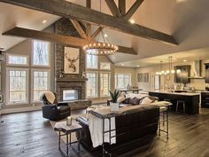 a living room filled with furniture and lots of windows next to a wooden floored kitchen