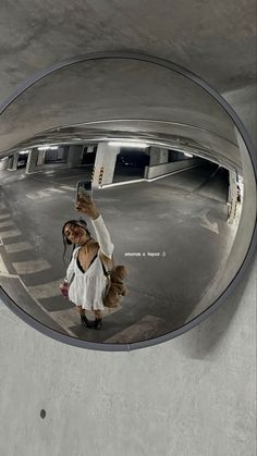 a woman taking a selfie with her cell phone in front of a round mirror