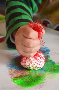 a child is playing with colored crayons on the table and making something out of paper