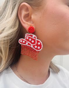 Product Details: Be the star of the show with these Patriotic Honky-Tonk Seed Bead Earrings! They come with a festive red cowboy hat that has a white star detail and a red rhinestone fringe. Get ready for some wild western-style fun with these statement earrings! Product Dimensions: 3" drop length. 2.5" wide. Handmade Red Beaded Earrings For 4th Of July, Western Style Red Jewelry As Gift, Red Beaded Earrings For 4th Of July, Red Star-shaped Beaded Jewelry, Fun Red Adjustable Earrings, Red Festive Earrings For Summer, Red Beaded Earrings For Summer Festival, Red Star-shaped Jewelry For Parties, Red Star-shaped Party Jewelry