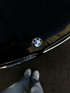 the front end of a bmw car with someone's feet propped up on it