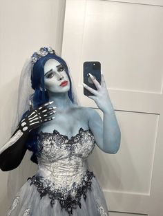 a woman with blue hair and makeup is taking a selfie in her wedding dress