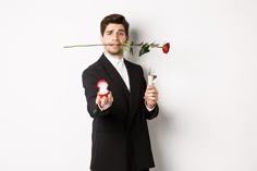 a man in a tuxedo holding two roses and a bottle with a lipstick on it