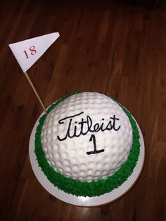 a golf ball cake with the number one on it and a flag in the middle