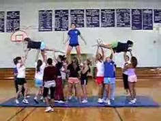 a group of people standing on top of a basketball court holding up their hands in the air