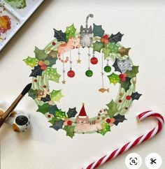 a christmas wreath with cats, holly and candy canes on the table next to it