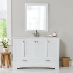 a white bathroom vanity with a mirror above it