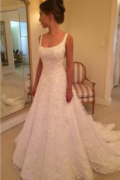 a woman standing in front of a mirror wearing a wedding dress