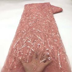 a hand is touching the back of a pink dress with sequins on it