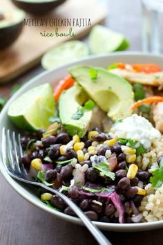 a white bowl filled with rice, black beans and avocado on top of a wooden table