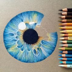 a drawing of an eye with colored pencils next to it