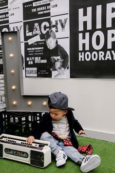 a young boy sitting on the ground playing with an old school style boombox in his living room