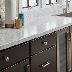 a kitchen with marble counter tops and stainless steel appliances in the middle, along with large windows