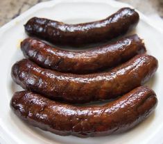 three sausages on a white plate sitting on a counter