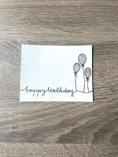 a happy birthday card with balloons on the front and back, sitting on a wooden surface