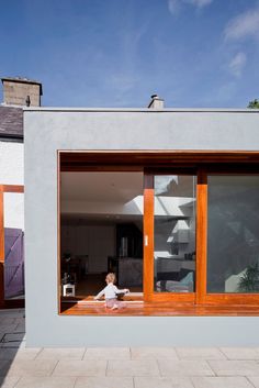 a small child sitting in the window of a house