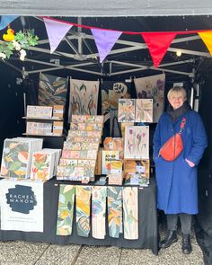 a woman standing in front of a booth selling greeting cards