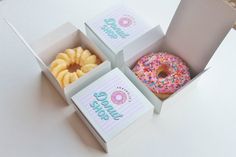 three donuts with sprinkles are in a box on the white table