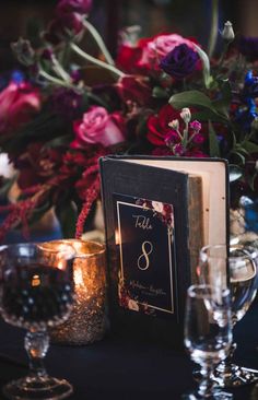 the table is set with candles, flowers and an open book on top of it