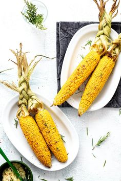 two plates with corn on the cob and herbs