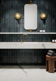 a bathroom with marble counter tops and dark green tiles on the walls, along with a gold faucet